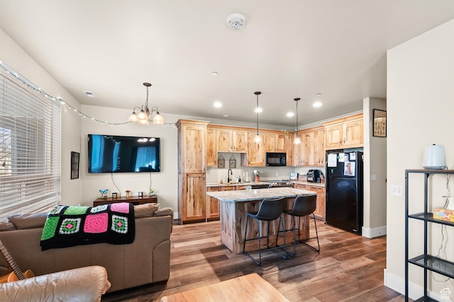 kitchen with open floor plan, light brown cabinets, and black appliances