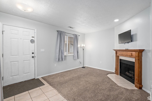 137 W 600 N Unit 205, Tooele, UT 84074 - unfurnished living room with visible vents, a textured ceiling, a fireplace, baseboards, and light colored carpet