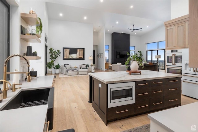 2940 Naomi Dr, North Logan, UT 84341 - kitchen featuring stainless steel microwave, light countertops, a sink, open floor plan, and a kitchen island