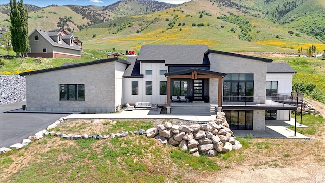 2940 Naomi Dr, North Logan, UT 84341 - back of property with a patio, board and batten siding, outdoor lounge area, a deck with mountain view, and stone siding