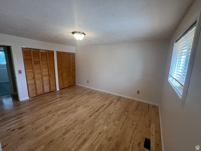 916 E Sunburn Ln, Sandy, UT 84094 - unfurnished bedroom with multiple windows, two closets, and light wood-style flooring