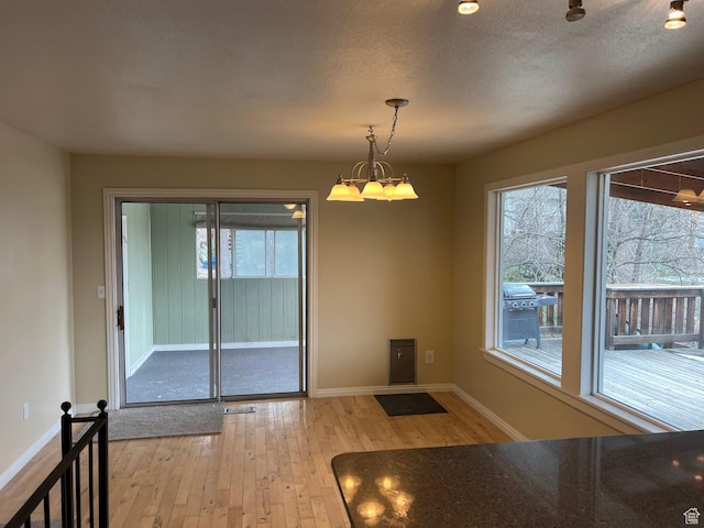 916 E Sunburn Ln, Sandy, UT 84094 - unfurnished dining area with baseboards, a healthy amount of sunlight, light wood-type flooring, and a textured ceiling