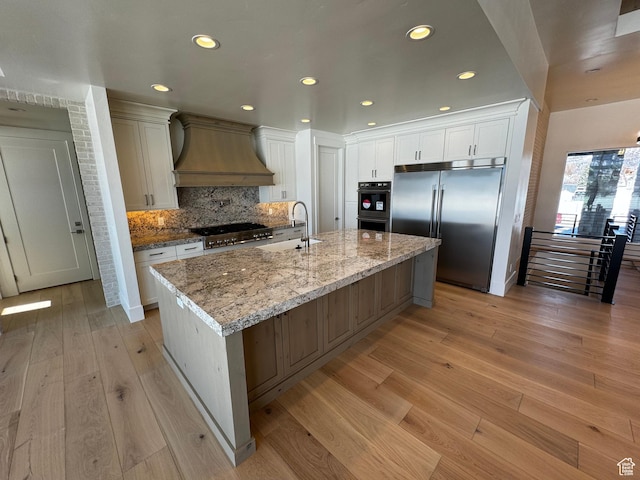 3151 E 5225 N Unit 11, Liberty, UT 84310 - kitchen with light wood-type flooring, premium range hood, dobule oven black, stainless steel built in fridge, and a sink