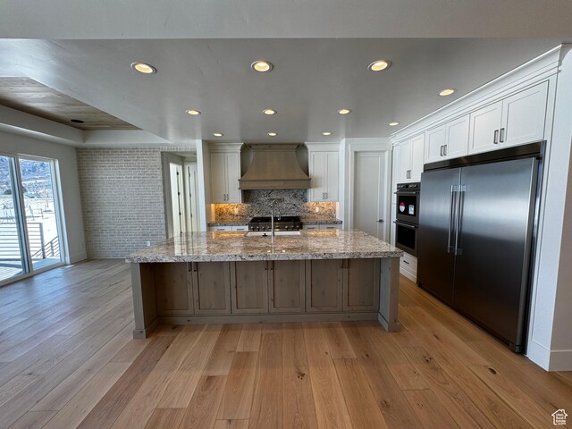 3151 E 5225 N Unit 11, Liberty, UT 84310 - kitchen with white cabinets, light wood-style flooring, premium range hood, and appliances with stainless steel finishes