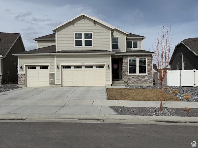 view of front of house featuring driveway, a gate, stone siding, fence, and a garage