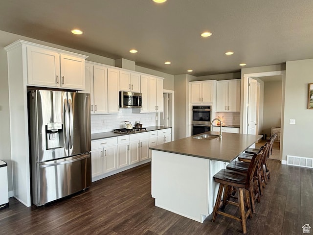 kitchen featuring dark countertops, visible vents, dark wood finished floors, and stainless steel appliances