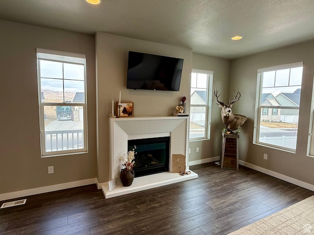 unfurnished living room featuring visible vents, a fireplace with raised hearth, baseboards, and hardwood / wood-style floors