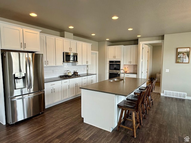 kitchen featuring visible vents, dark wood-type flooring, dark countertops, and appliances with stainless steel finishes