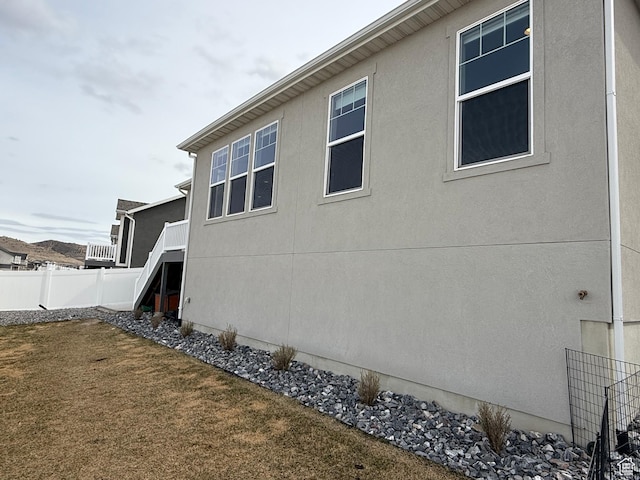 view of side of property with stucco siding, a yard, and fence