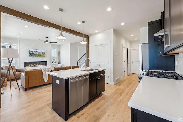 6005 N Westridge Rd, Heber City, UT 84032 - kitchen featuring a large fireplace, a ceiling fan, appliances with stainless steel finishes, a sink, and backsplash