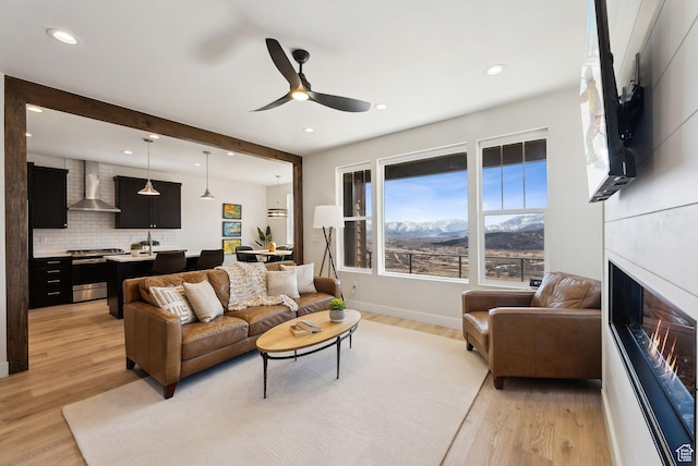 6005 N Westridge Rd, Heber City, UT 84032 - living room with light wood finished floors, a lit fireplace, beam ceiling, and a ceiling fan
