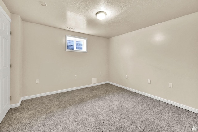 below grade area with baseboards, visible vents, carpet, and a textured ceiling