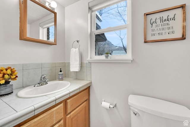 half bathroom with toilet, decorative backsplash, and vanity