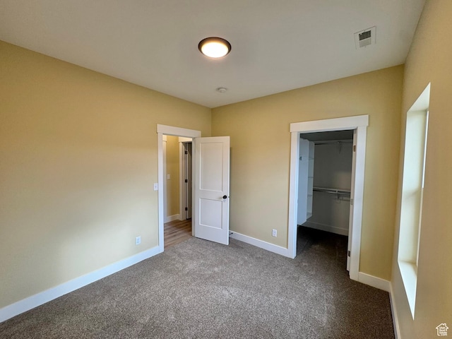 18136 N 6000 W, Garland, UT 84312 - unfurnished bedroom with visible vents, a walk in closet, dark carpet, a closet, and baseboards