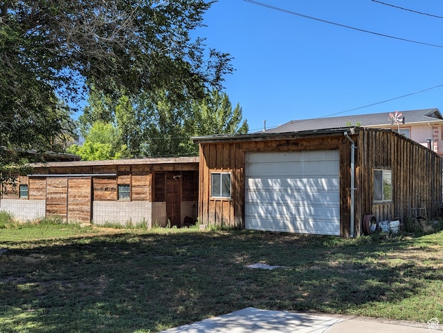 view of front of home featuring driveway, an attached garage, an outdoor structure, and board and batten siding