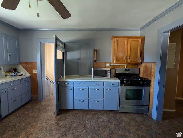 kitchen featuring ceiling fan, stainless steel appliances, wood walls, and light countertops