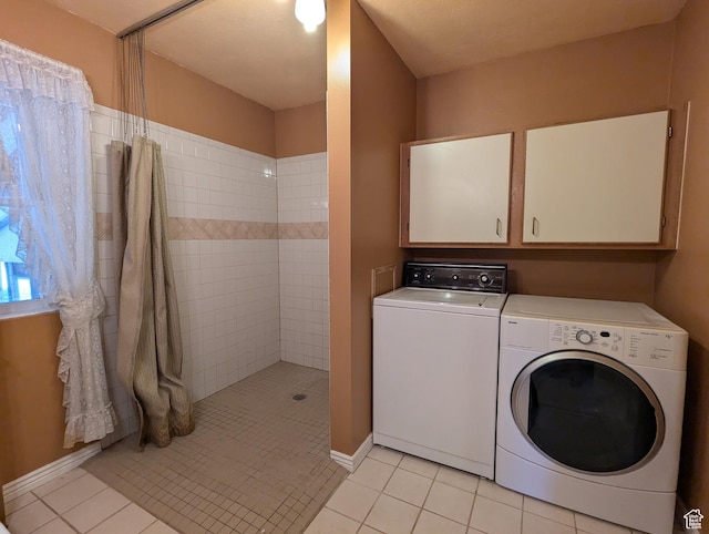 clothes washing area with baseboards, light tile patterned flooring, laundry area, and washer and clothes dryer