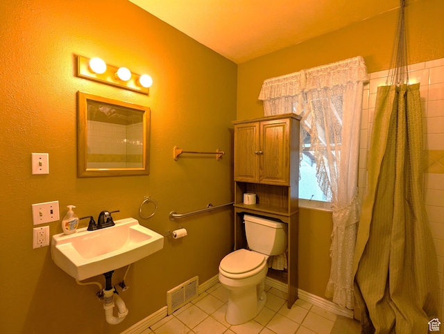 bathroom featuring visible vents, baseboards, toilet, tile patterned floors, and a sink