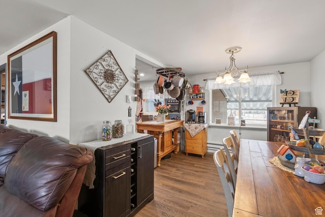 dining area featuring a baseboard heating unit, an inviting chandelier, and wood finished floors