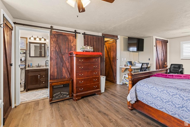 bedroom with a sink, a textured ceiling, a barn door, and wood finished floors