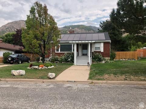 3614 Taylor Ave, Ogden, UT 84403 - bungalow-style house with a mountain view, solar panels, a chimney, fence, and a front yard