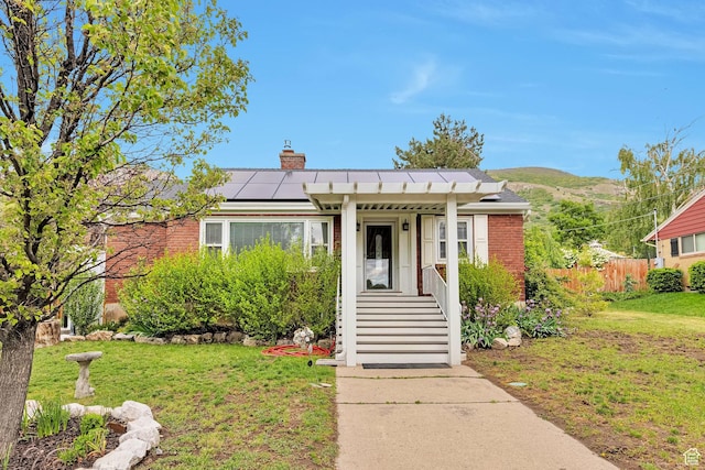 3614 Taylor Ave, Ogden, UT 84403 - view of front of home with roof mounted solar panels, brick siding, a chimney, and a mountain view