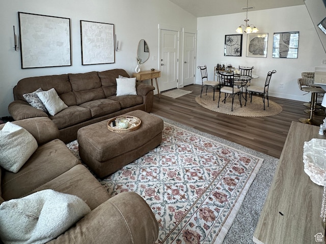 living room featuring baseboards, lofted ceiling, an inviting chandelier, and wood finished floors
