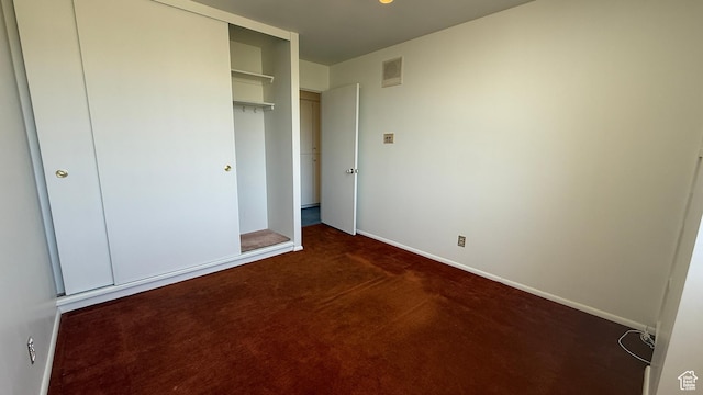 777 E S Temple Unit 13A, Salt Lake City, UT 84102 - unfurnished bedroom with dark carpet, baseboards, and a closet