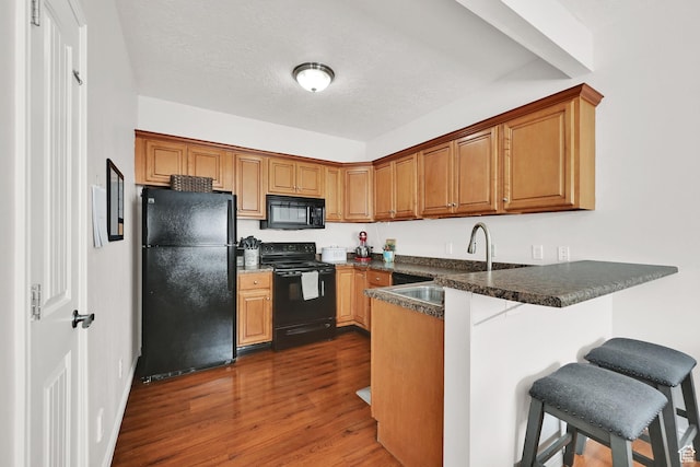462 W 1490 N Unit 102, Logan, UT 84341 - kitchen with black appliances, a sink, a peninsula, dark wood-type flooring, and a breakfast bar area