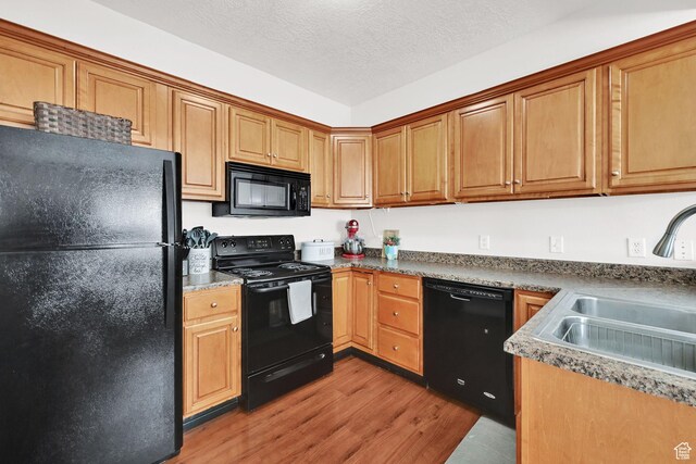 462 W 1490 N Unit 102, Logan, UT 84341 - kitchen featuring black appliances, a sink, light wood-type flooring, a textured ceiling, and brown cabinetry