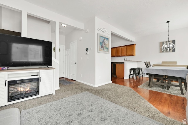 462 W 1490 N Unit 102, Logan, UT 84341 - living area featuring a chandelier, baseboards, a lit fireplace, and wood finished floors