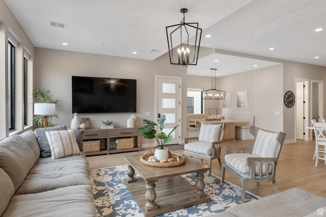 living room with an inviting chandelier, a healthy amount of sunlight, visible vents, and light wood-type flooring