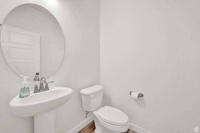 bathroom featuring a sink, baseboards, toilet, and wood finished floors