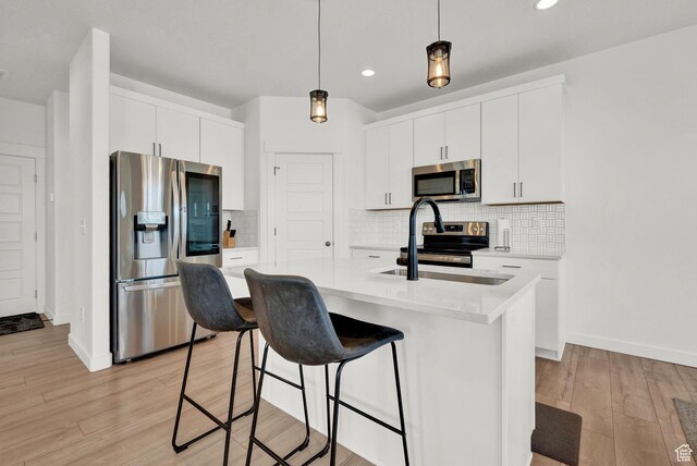 kitchen with pendant lighting, light wood-style flooring, stainless steel appliances, a breakfast bar area, and light countertops