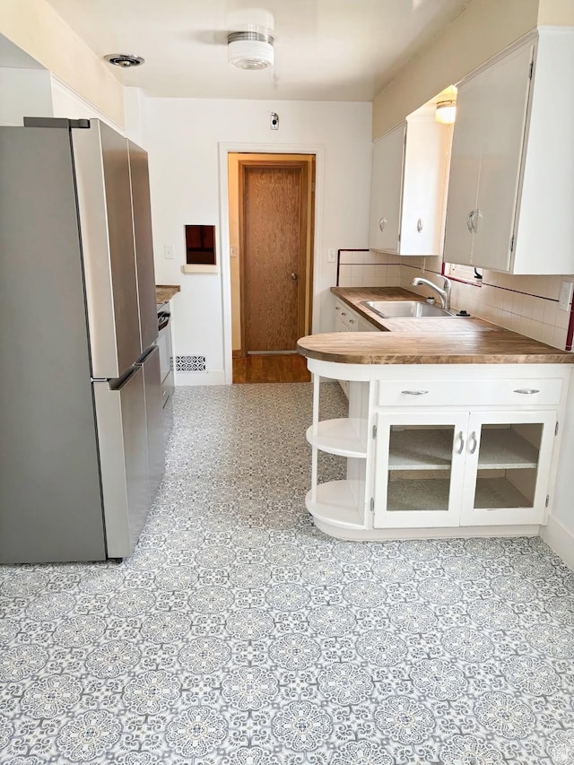 175 E 700 N, Logan, UT 84321 - kitchen featuring baseboards, freestanding refrigerator, a sink, white cabinetry, and tasteful backsplash