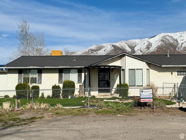 view of front of property featuring a shingled roof, a mountain view, and a fenced front yard