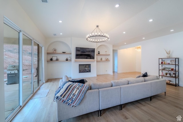 1683 S Painted Vista Cir, Washington, UT 84780 - living room featuring built in shelves, recessed lighting, light wood-style floors, an inviting chandelier, and a glass covered fireplace