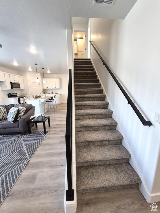 200 S 460 W Unit 4, Delta, UT 84624 - staircase featuring visible vents, wood finished floors, baseboards, and a textured ceiling