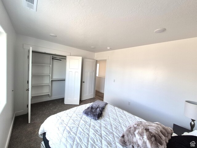 200 S 460 W Unit 4, Delta, UT 84624 - bedroom with visible vents, a textured ceiling, dark carpet, a closet, and baseboards