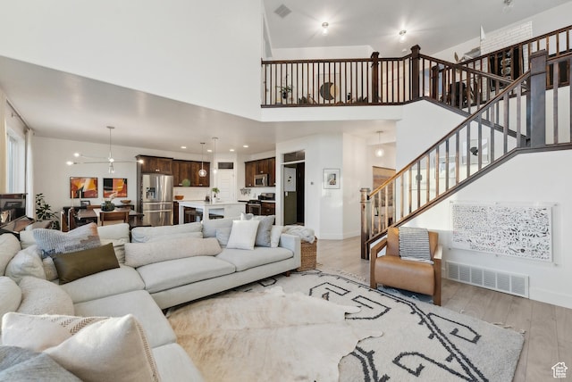 2101 W 980 S, Orem, UT 84059 - living area with visible vents, ceiling fan, light wood-style floors, a towering ceiling, and stairs