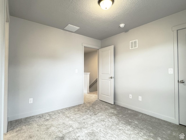 spare room with visible vents, carpet floors, a textured ceiling, and baseboards