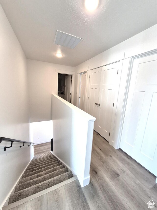 staircase with visible vents and wood finished floors