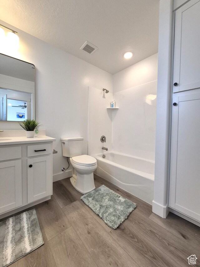full bathroom with visible vents, toilet, shower / bathtub combination, wood finished floors, and vanity