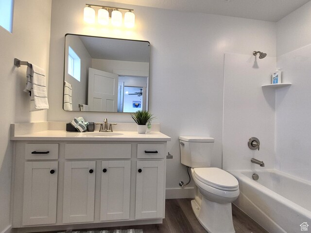 bathroom with toilet, shower / bathtub combination, wood finished floors, baseboards, and vanity