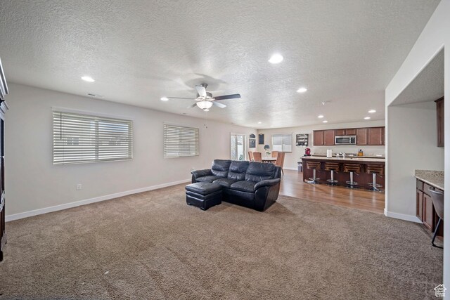 living room featuring a textured ceiling, recessed lighting, carpet flooring, baseboards, and ceiling fan