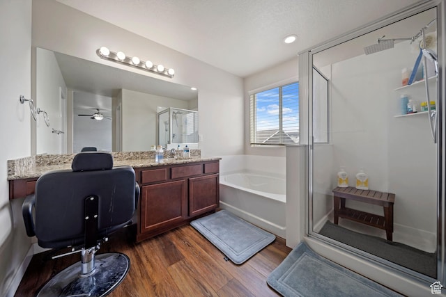 full bathroom featuring vanity, wood finished floors, a stall shower, ceiling fan, and a garden tub