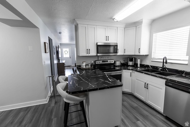 832 S 1430 E, Spanish Fork, UT 84660 - kitchen featuring stainless steel appliances, dark countertops, white cabinetry, dark wood finished floors, and a textured ceiling