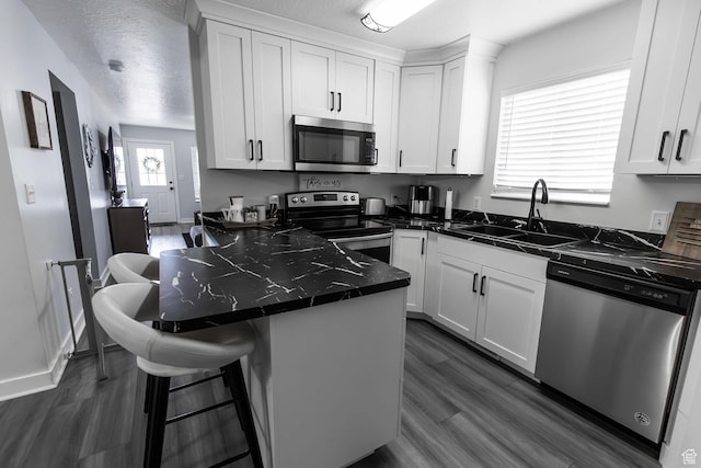 832 S 1430 E, Spanish Fork, UT 84660 - kitchen featuring stainless steel appliances, a sink, dark countertops, white cabinets, and a breakfast bar
