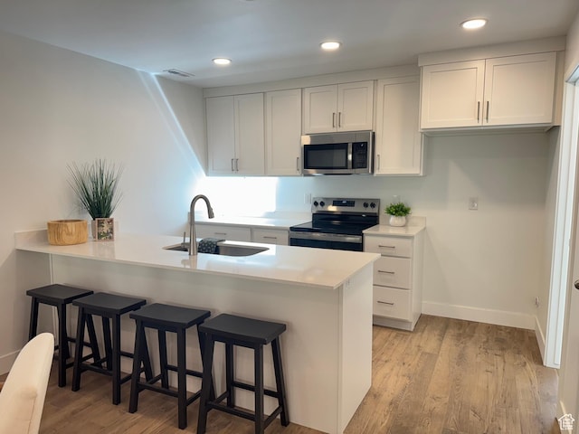 1590 S 900 W Unit 902, Salt Lake City, UT 84104 - kitchen featuring visible vents, stainless steel appliances, a sink, light wood-style floors, and a kitchen breakfast bar