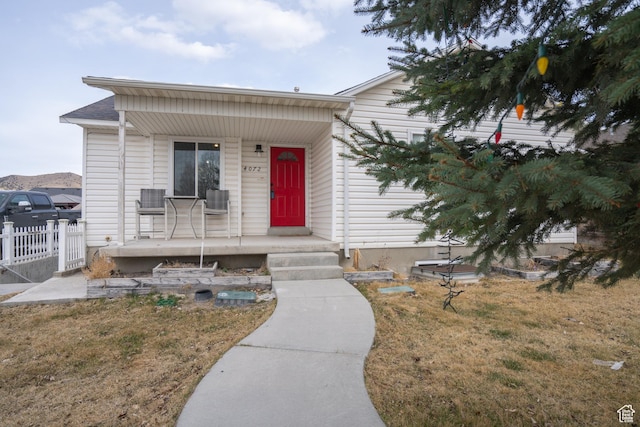 view of front of property featuring a porch, fence, and a front yard